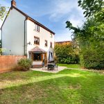 Three-storey house with garden and patio furniture.