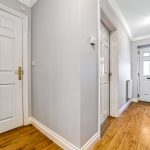 Bright hallway with wooden floor and white doors.