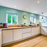 Modern kitchen with white cabinets and wooden floor.