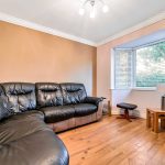 Modern lounge with leather sofa and bay window.