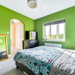 Bright bedroom with green walls and floral bedding.