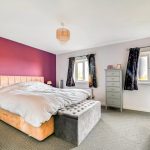 Modern bedroom with purple accent wall and furniture.