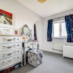 Cosy bedroom with dresser, mirror, and window curtains.