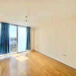 Bright empty room with wooden floor and blue curtains.