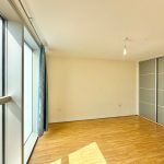 Bright empty room with wooden floor and large window.