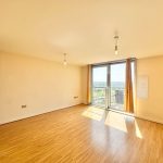 Bright empty room with wooden floor and large windows.