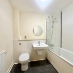 Modern white bathroom with toilet, sink, and bath.