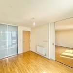 Bright empty room with wooden flooring.