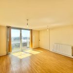 Bright empty room with wooden floor and large window.