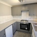 Modern grey kitchen with appliances and tiled backsplash.
