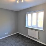 Empty grey room with window and radiator.