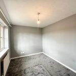 Empty grey-walled room with carpet and window
