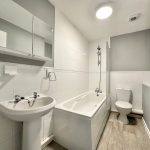 Modern white bathroom with bathtub and toilet.