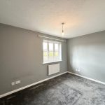 Empty grey room with window and light fixture.