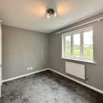 Empty bedroom with grey walls and carpet.