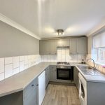 Modern grey kitchen with tiled backsplash and appliances.