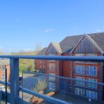 View from balcony overlooking residential buildings and countryside.