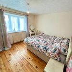Cosy bedroom with floral bedding and pastel curtains.