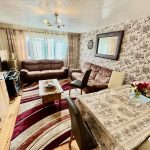 Cosy living room with floral wallpaper and sofas.