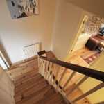 Wooden staircase with hallway view, chandelier visible.