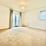 Bright empty room with carpet and balcony doors.