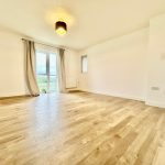 Spacious room with wooden flooring and large window.