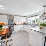 Modern kitchen with white cabinets and dining table.