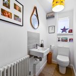 Modern white bathroom with framed photos and round mirror.