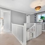 Upstairs landing with grey walls and white railings.