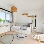 Bright bedroom with modern decor and elephant stool.