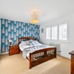 Bright bedroom with blue patterned feature wall.