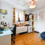 Colourful home office with abstract decor and bookshelf.