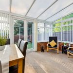 Bright conservatory with chairs and dining table.