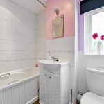 Modern bathroom with white tiles and pink accents.
