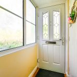 Sunny yellow hallway with decorative white front door.