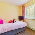 Cosy bedroom with plush toy and television.