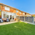 Suburban garden with patio and brick house backdrop.