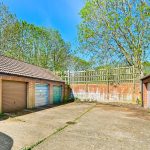 Row of garages with brick walls and trees.