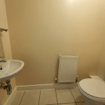 Small bathroom with sink, toilet, radiator.