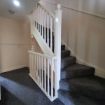 Carpeted staircase with white wooden railing.