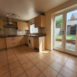 Spacious kitchen with garden view through doors.