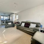 Open living room with leather sofas and kitchen