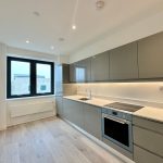 Modern kitchen with grey cabinets and natural light.