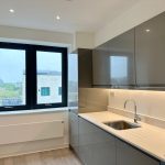 Modern kitchen with grey cabinets and window view.