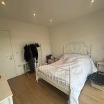 Minimalist bedroom with white bed and wardrobe.