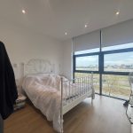 Bright bedroom with large window and double bed.