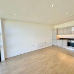 Modern kitchen in bright empty apartment with wood floor.