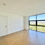 Empty room with large window and wooden floor.