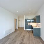 Modern kitchen in empty apartment with wooden flooring.