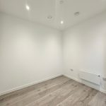 Empty modern room with white walls and wood floor.